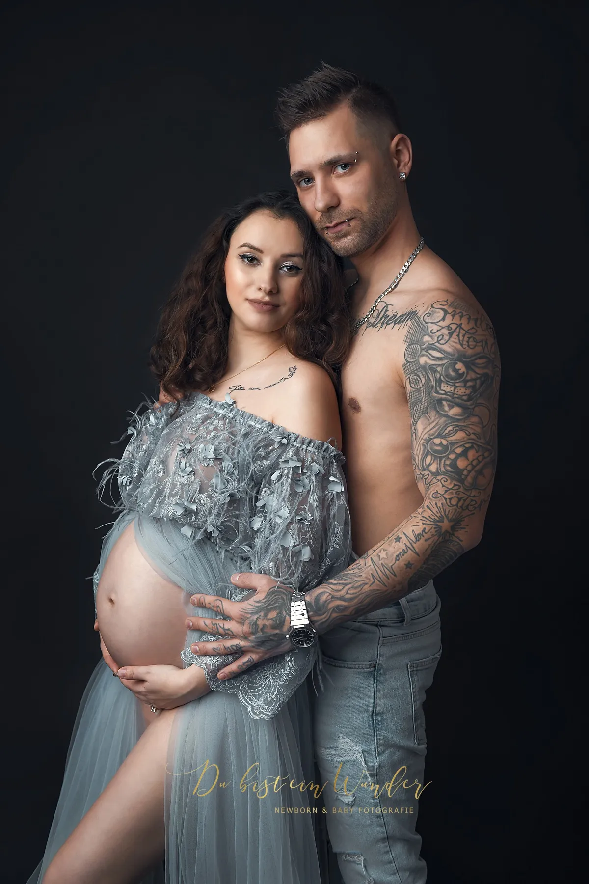 Paarfoto im Studio, sie im grauen Tüllkleid vor dunklem Hintergrund