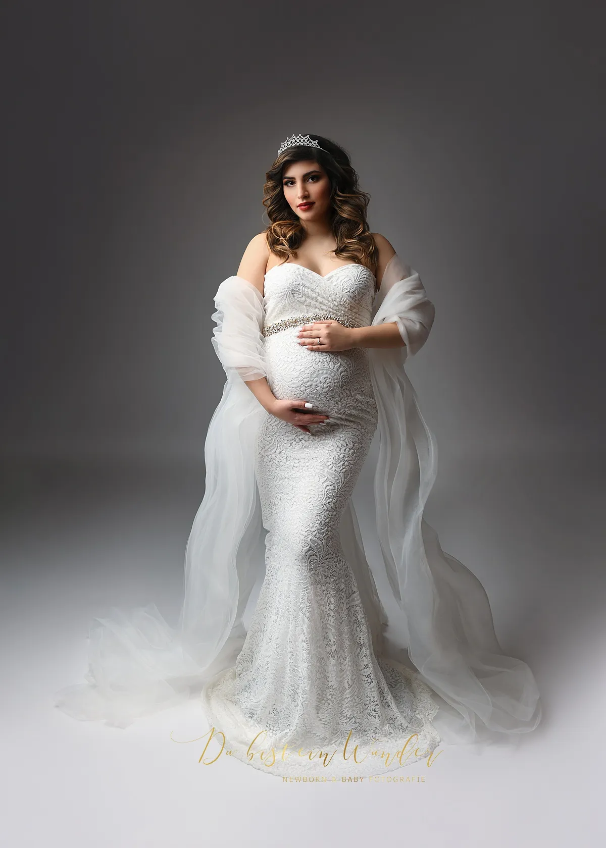 Babybauch Fotografie im weißen Spitzenkleid mit Schleier und Krone im Studio