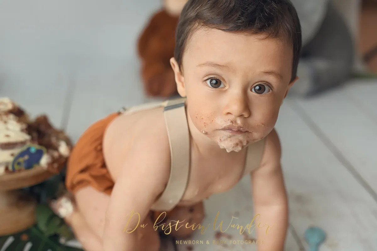 Lächelnder sitzender Junge beim Boho Cake Smash