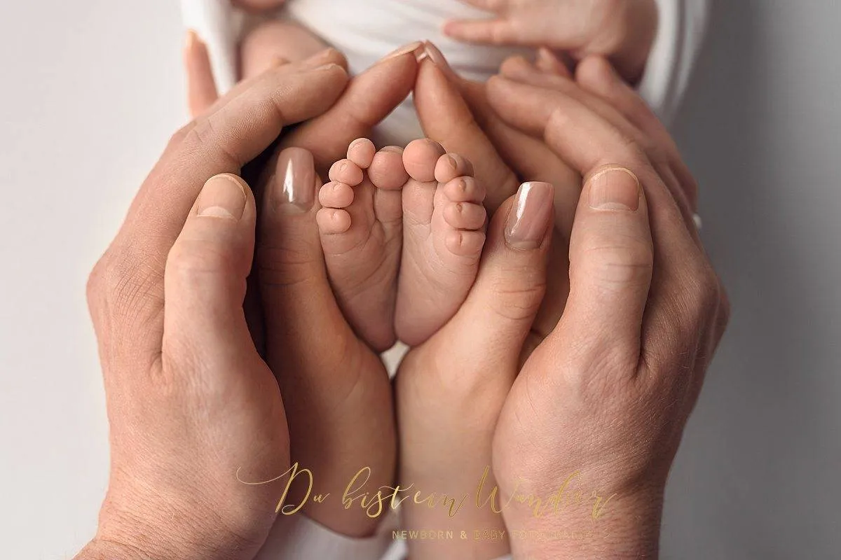 Elternhände halten zärtlich die winzigen Füße ihres neugeborenen Babys