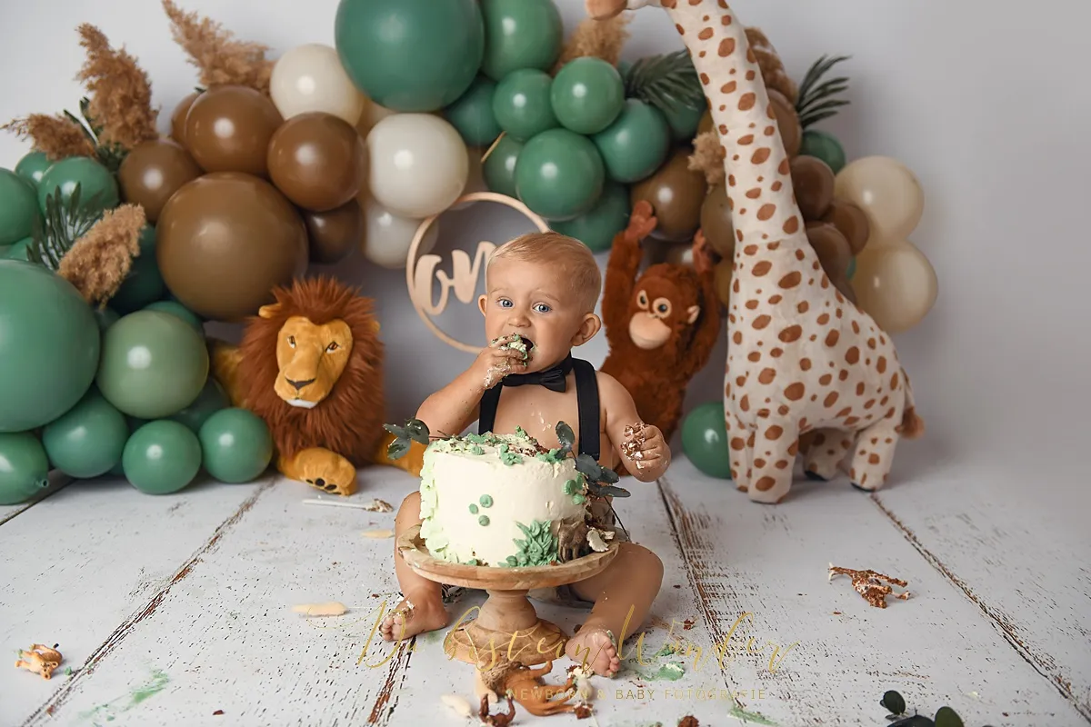 Kleiner Junge nascht von Safari-Torte beim Cake-Smash Shooting mit Dschungel-Deko