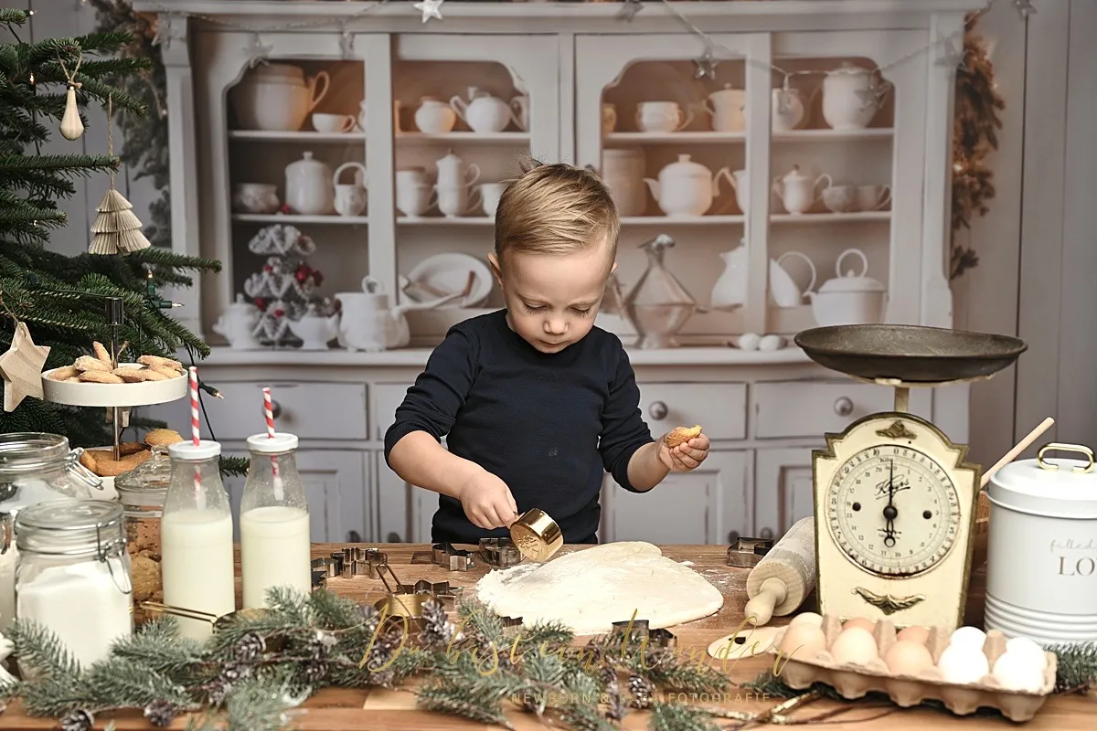 Kleiner Junge sticht konzentriert Plätzchen aus in der weihnachtlichen Backstube