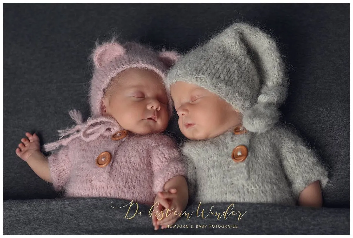 Schlafende neugeborene Zwillinge in rosa und grauen Strickoutfits