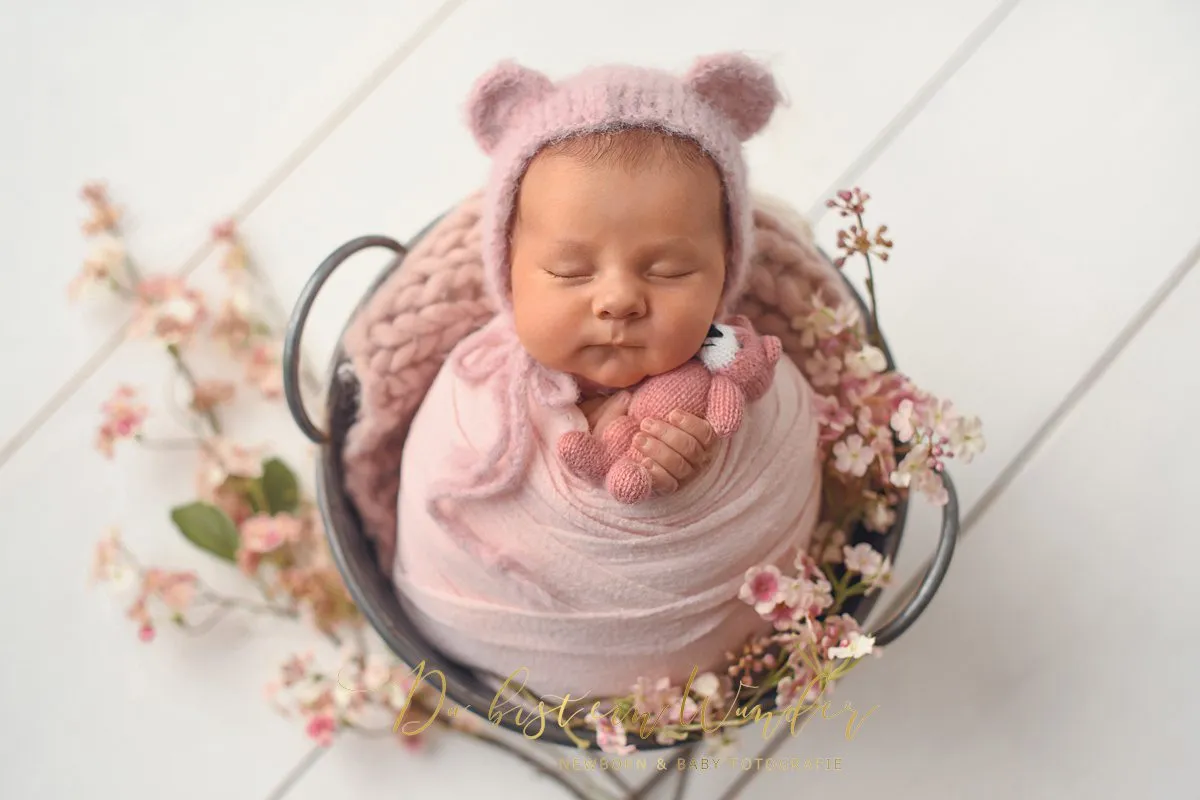 Newborn Portrait im weißen Anzug auf Bett