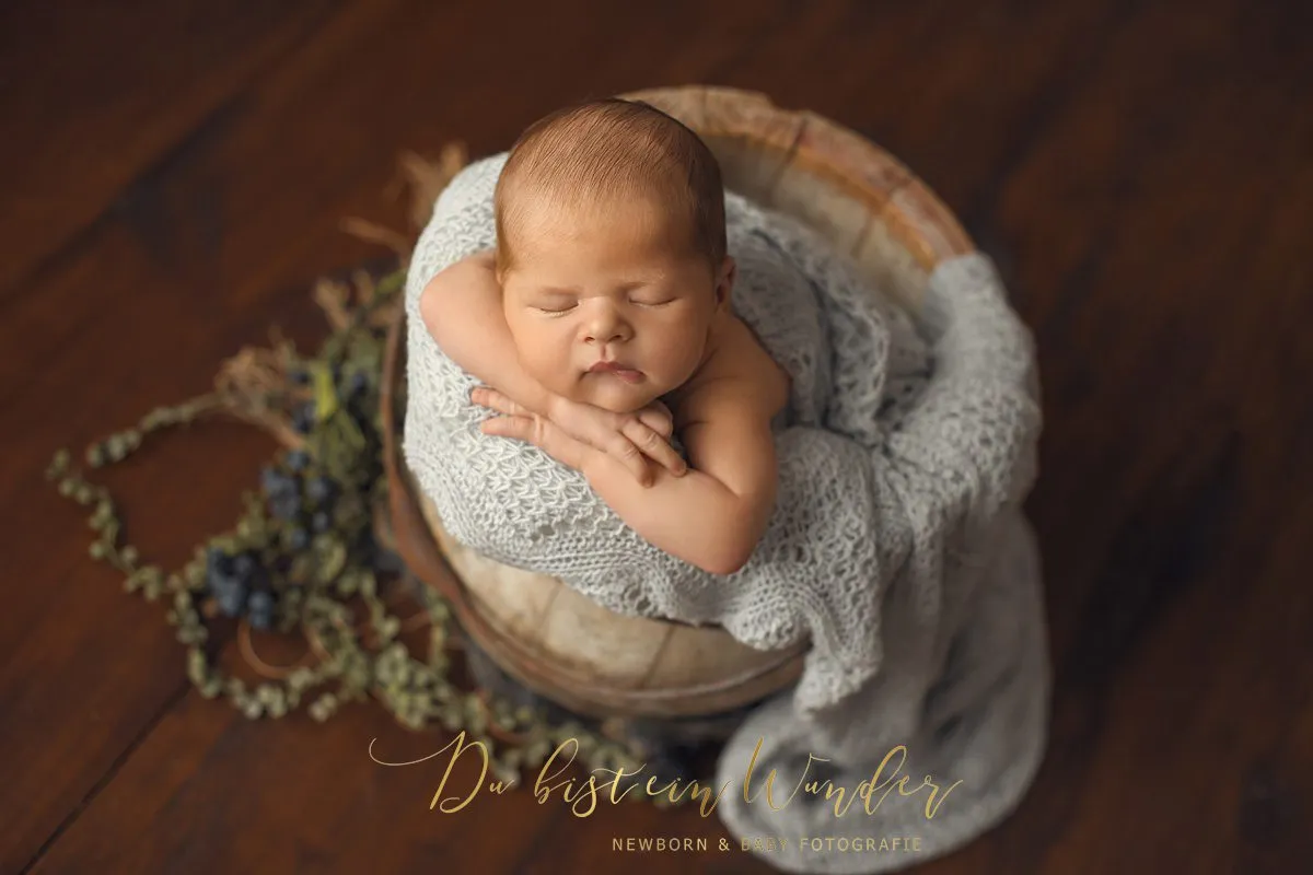 Baby im grauen Korb mit Blumendeko