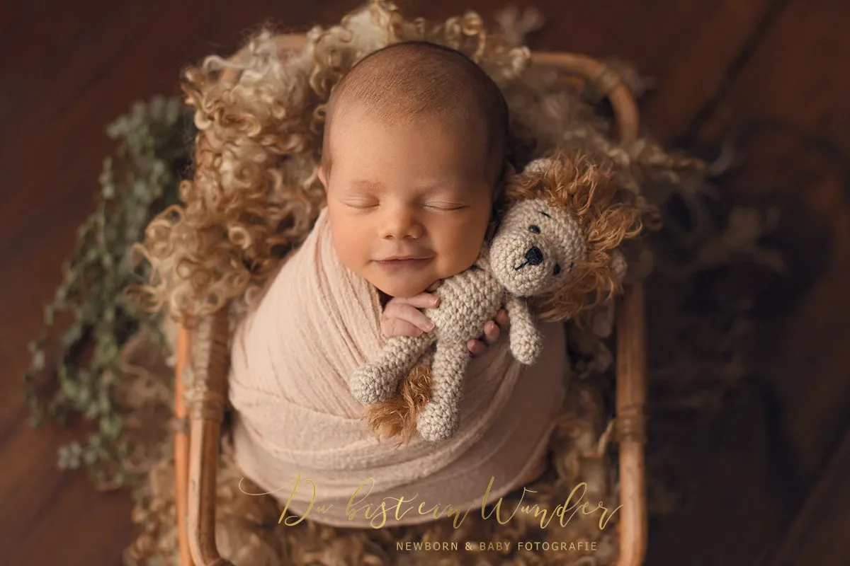 Newborn im rosa Korb mit Strickdecke