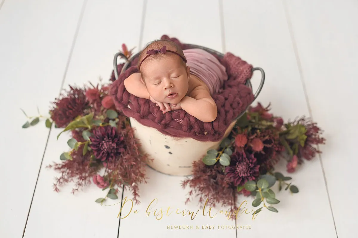 Baby mit Zipfelmütze im grauen Bett