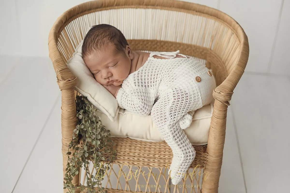 Neugeborenes Baby im Korb mit beiger Strickdecke