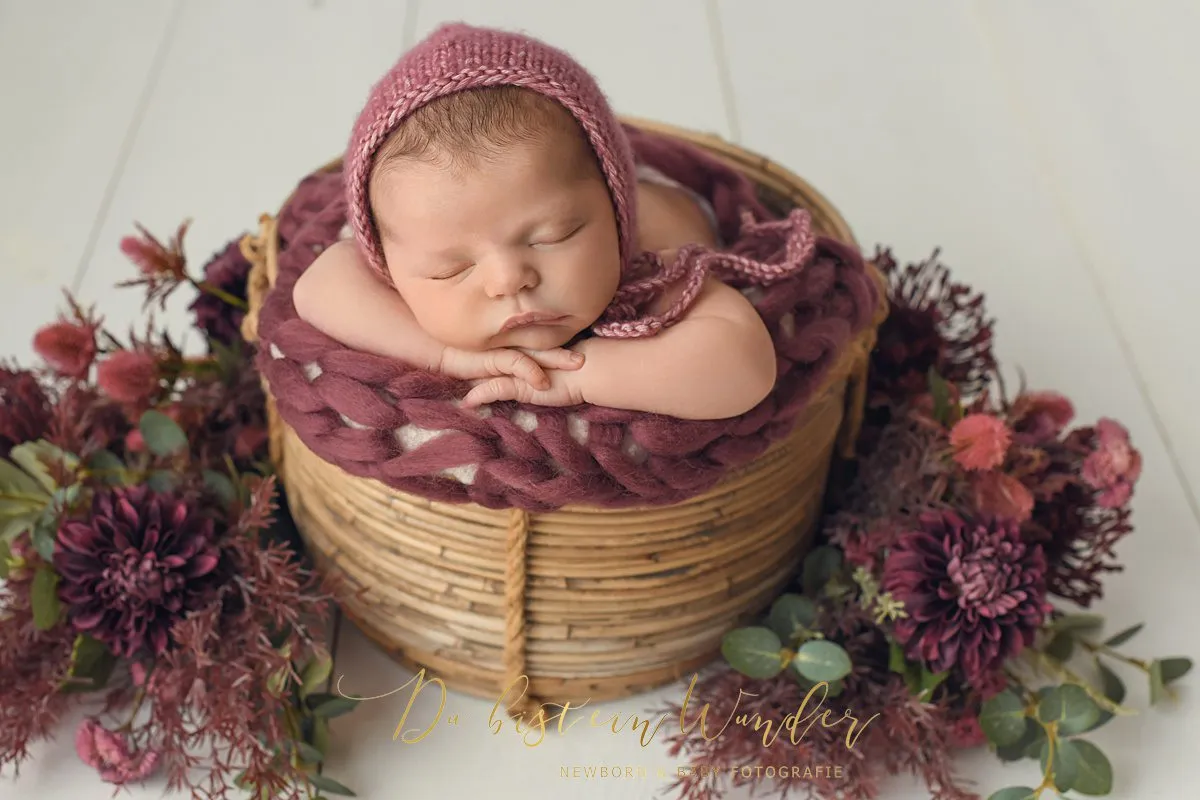 Baby im grauen Korb mit Strickdecke