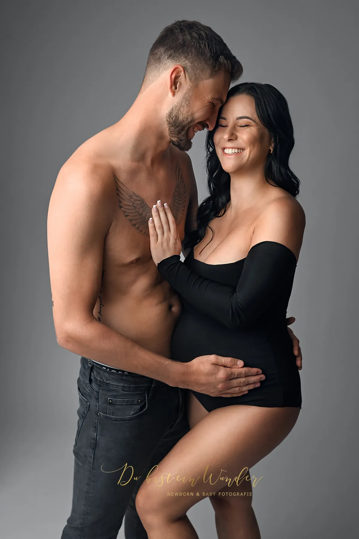 Lachendes Paar beim Schwangerschaftsshooting in schwarzem Outfit