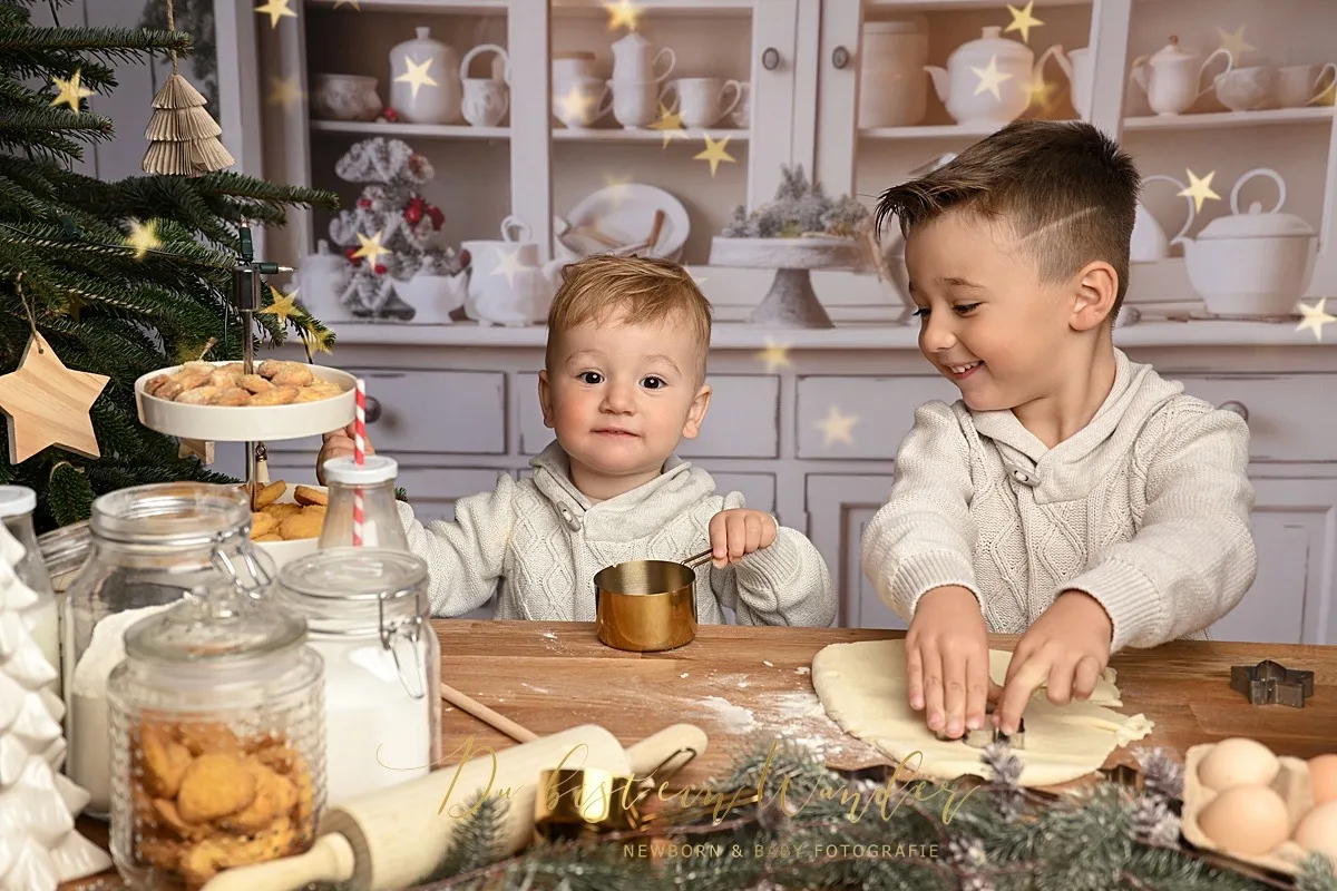 Zwei Brüder backen gemeinsam Plätzchen in der Weihnachtsbäckerei mit goldenen Sternen