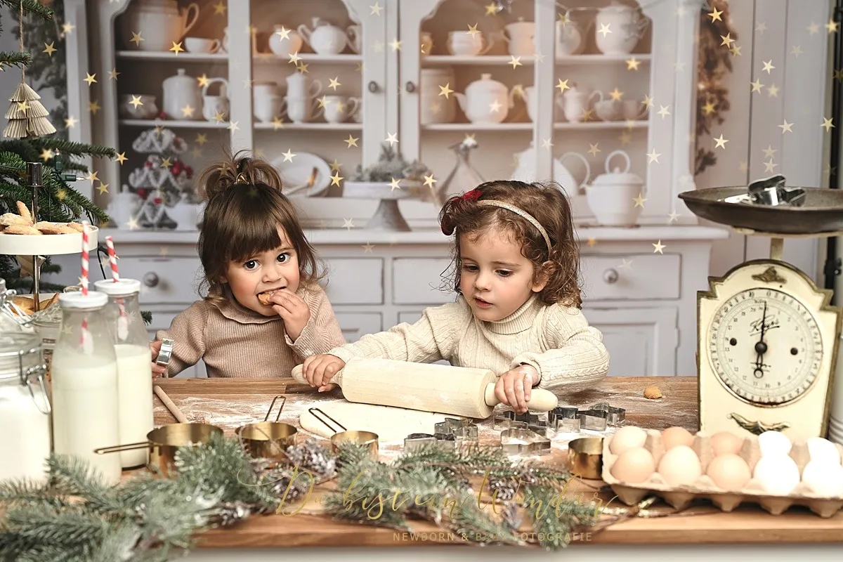 Zwei Schwestern backen Plätzchen in der weihnachtlichen Backstube mit goldenen Sternen