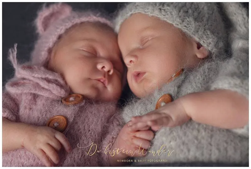 Nahaufnahme der neugeborenen Zwillinge aneinander gekuschelt in Strickkleidung